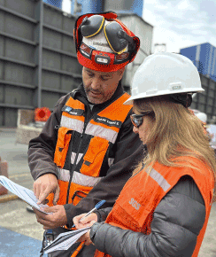Dos colaboradores de RMC Corporate en terreno revisando planos y documentación técnica de un proyecto industrial.
